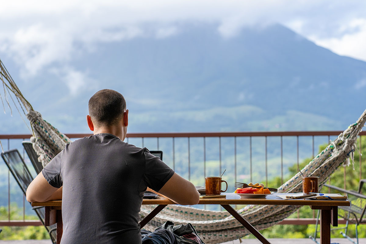 Man sitting on a table with breakfast while working with a view Digital nomad costa rica
